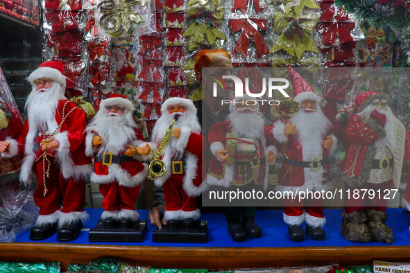 A man sets up various Santa Claus dolls for sale. A shop sells decoration items for Christmas at a market in Kolkata, India, on December 18,...