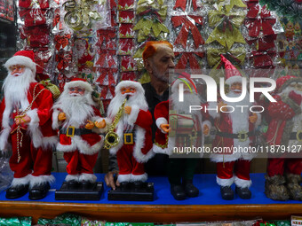 A man sets up various Santa Claus dolls for sale. A shop sells decoration items for Christmas at a market in Kolkata, India, on December 18,...