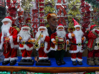 A man sets up various Santa Claus dolls for sale. A shop sells decoration items for Christmas at a market in Kolkata, India, on December 18,...