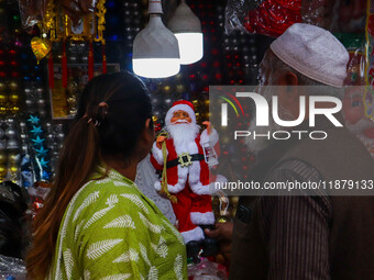 A lady shops for a Santa Claus doll as a shop sells decoration items for Christmas at a market in Kolkata, India, on December 18, 2024. (