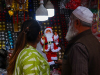 A lady shops for a Santa Claus doll as a shop sells decoration items for Christmas at a market in Kolkata, India, on December 18, 2024. (