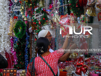 A lady shops for a Santa Claus doll as a shop sells decoration items for Christmas at a market in Kolkata, India, on December 18, 2024. (