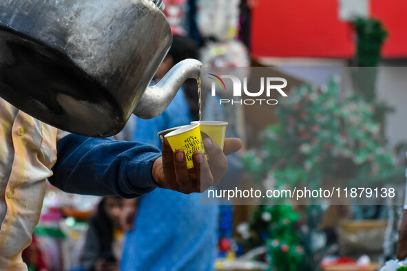 A tea seller pours hot tea into styrofoam cups in Kolkata, India, on December 18, 2024. 