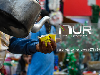 A tea seller pours hot tea into styrofoam cups in Kolkata, India, on December 18, 2024. (