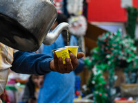 A tea seller pours hot tea into styrofoam cups in Kolkata, India, on December 18, 2024. (