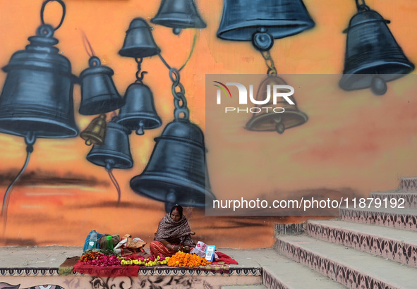 A woman sells flowers outside a temple in Prayagraj, India, on December 18, 2024. 