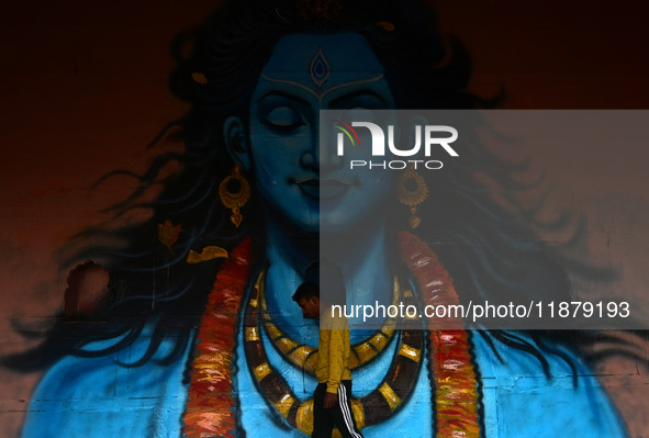 A man walks past a mural painting of Lord Shiva on the wall of a temple, created as part of the ongoing 'Paint My City' project for the upco...