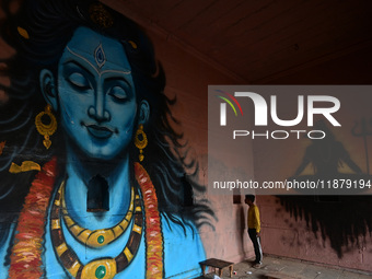 A man stands next to a mural painting of Lord Shiva on the wall of a temple, created as part of the ongoing 'Paint My City' project for the...