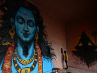 A man stands next to a mural painting of Lord Shiva on the wall of a temple, created as part of the ongoing 'Paint My City' project for the...