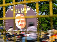 Motorists commute next to the banner that says ''Modi-Adani are brothers'' during a protest by Indian National Congress (INC) workers agains...