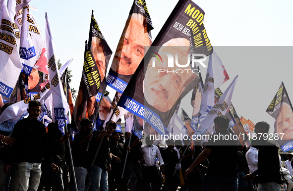 Indian National Congress (INC) workers carry flags that say ''Modi-Adani are brothers'' during a protest against the inaction of India's Pri...