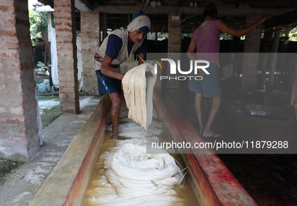 A weaver cleans cotton yarn with water before it dries for making a saree, a traditional cloth used for women's clothing, at a workshop in S...