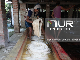 A weaver cleans cotton yarn with water before it dries for making a saree, a traditional cloth used for women's clothing, at a workshop in S...