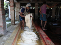 A weaver cleans cotton yarn with water before it dries for making a saree, a traditional cloth used for women's clothing, at a workshop in S...