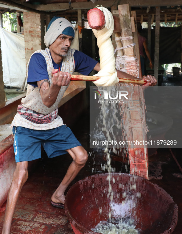 A weaver removes water from cotton yarn before it dries for making a saree, a traditional cloth used for women's clothing, at a workshop in...