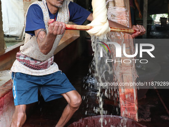 A weaver removes water from cotton yarn before it dries for making a saree, a traditional cloth used for women's clothing, at a workshop in...