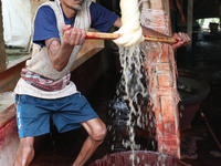 A weaver removes water from cotton yarn before it dries for making a saree, a traditional cloth used for women's clothing, at a workshop in...