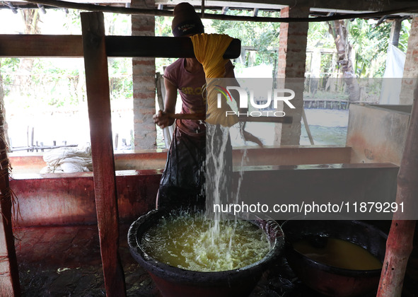 A weaver removes water from threads after coloring them, before they dry, for making a saree, a traditional cloth used for women's clothing,...