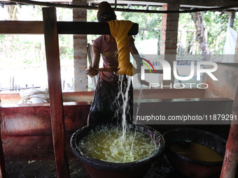 A weaver removes water from threads after coloring them, before they dry, for making a saree, a traditional cloth used for women's clothing,...