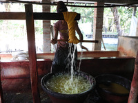 A weaver removes water from threads after coloring them, before they dry, for making a saree, a traditional cloth used for women's clothing,...