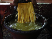 A weaver removes water from threads after coloring them, before they dry, for making a saree, a traditional cloth used for women's clothing,...