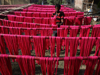 A weaver dries threads before weaving a saree, a traditional cloth used for women's clothing, at a workshop in Santipur town, about 80 km fr...