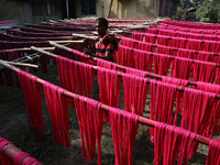 A weaver dries threads before weaving a saree, a traditional cloth used for women's clothing, at a workshop in Santipur town, about 80 km fr...