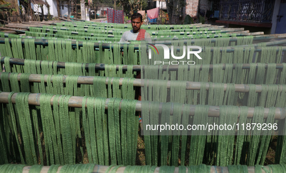 A weaver dries threads before weaving a saree, a traditional cloth used for women's clothing, at a workshop in Santipur town, about 80 km fr...