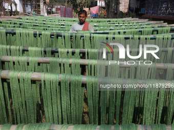 A weaver dries threads before weaving a saree, a traditional cloth used for women's clothing, at a workshop in Santipur town, about 80 km fr...