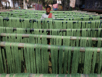 A weaver dries threads before weaving a saree, a traditional cloth used for women's clothing, at a workshop in Santipur town, about 80 km fr...