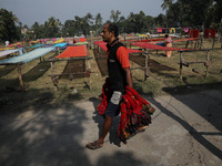 A weaver carries sarees, a traditional cloth used for women's clothing, to hang out to dry after weaving them at a workshop in Santipur, Ind...