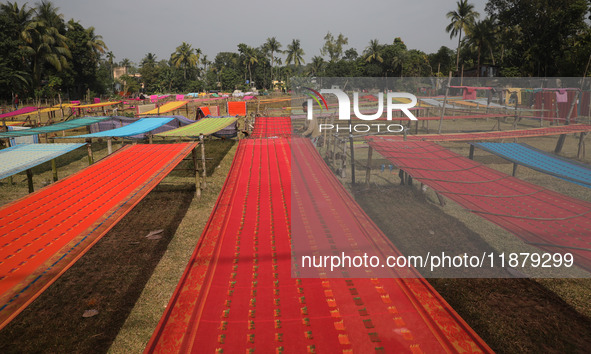 Weavers arrange sarees, a traditional cloth used for women's clothing, as they hang them out to dry after weaving at a workshop in Santipur...