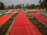 Weavers arrange sarees, a traditional cloth used for women's clothing, as they hang them out to dry after weaving at a workshop in Santipur...