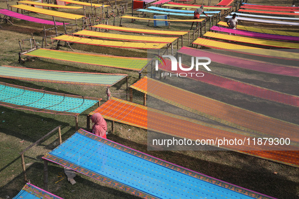 Weavers arrange sarees, a traditional cloth used for women's clothing, as they hang them out to dry after weaving at a workshop in Santipur...