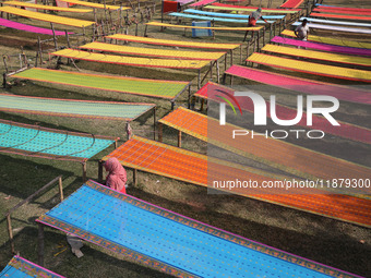 Weavers arrange sarees, a traditional cloth used for women's clothing, as they hang them out to dry after weaving at a workshop in Santipur...