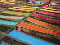 Weavers arrange sarees, a traditional cloth used for women's clothing, as they hang them out to dry after weaving at a workshop in Santipur...