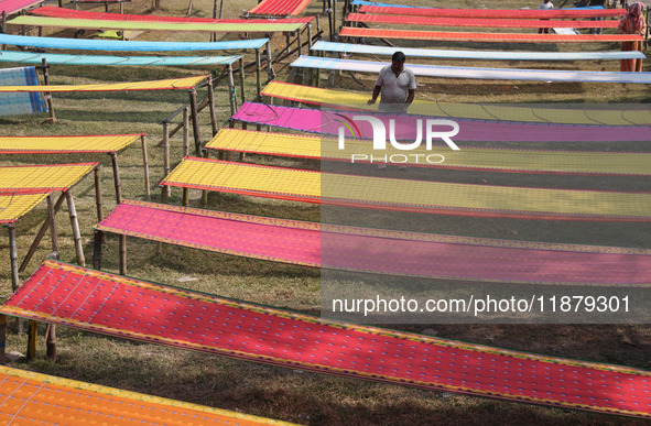 Weavers arrange sarees, a traditional cloth used for women's clothing, as they hang them out to dry after weaving at a workshop in Santipur...