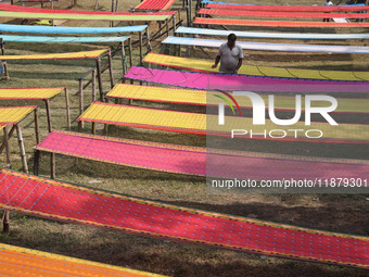 Weavers arrange sarees, a traditional cloth used for women's clothing, as they hang them out to dry after weaving at a workshop in Santipur...