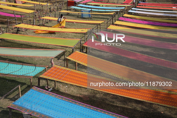 Weavers arrange sarees, a traditional cloth used for women's clothing, as they hang them out to dry after weaving at a workshop in Santipur...