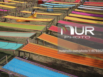 Weavers arrange sarees, a traditional cloth used for women's clothing, as they hang them out to dry after weaving at a workshop in Santipur...