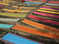 Weavers arrange sarees, a traditional cloth used for women's clothing, as they hang them out to dry after weaving at a workshop in Santipur...