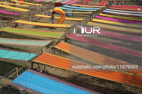 Weavers arrange sarees, a traditional cloth used for women's clothing, as they hang them out to dry after weaving at a workshop in Santipur...