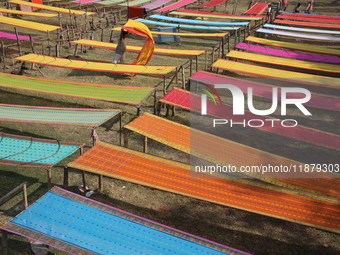 Weavers arrange sarees, a traditional cloth used for women's clothing, as they hang them out to dry after weaving at a workshop in Santipur...