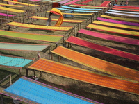 Weavers arrange sarees, a traditional cloth used for women's clothing, as they hang them out to dry after weaving at a workshop in Santipur...