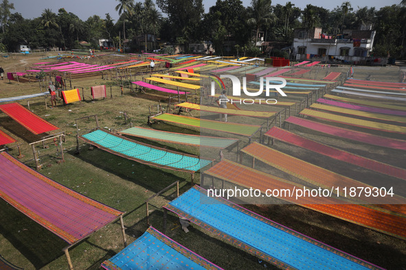 Weavers arrange sarees, a traditional cloth used for women's clothing, as they hang them out to dry after weaving at a workshop in Santipur...