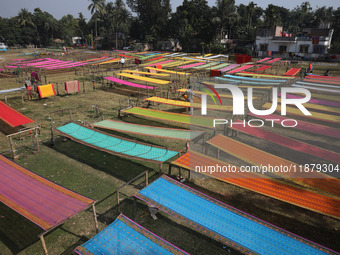 Weavers arrange sarees, a traditional cloth used for women's clothing, as they hang them out to dry after weaving at a workshop in Santipur...