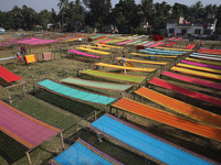 Weavers arrange sarees, a traditional cloth used for women's clothing, as they hang them out to dry after weaving at a workshop in Santipur...