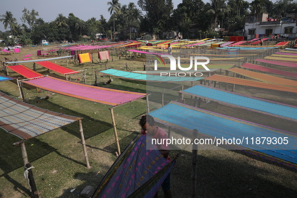 Weavers arrange sarees, a traditional cloth used for women's clothing, as they hang them out to dry after weaving at a workshop in Santipur...