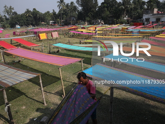 Weavers arrange sarees, a traditional cloth used for women's clothing, as they hang them out to dry after weaving at a workshop in Santipur...