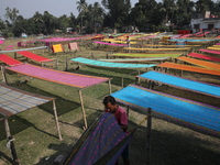 Weavers arrange sarees, a traditional cloth used for women's clothing, as they hang them out to dry after weaving at a workshop in Santipur...